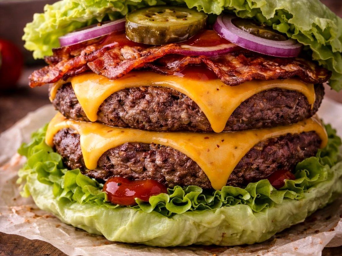 Classic Bacon-Cheeseburger im Salatblatt mit Rinderhack, Käse, Bacon, Gurke und roter Zwiebel